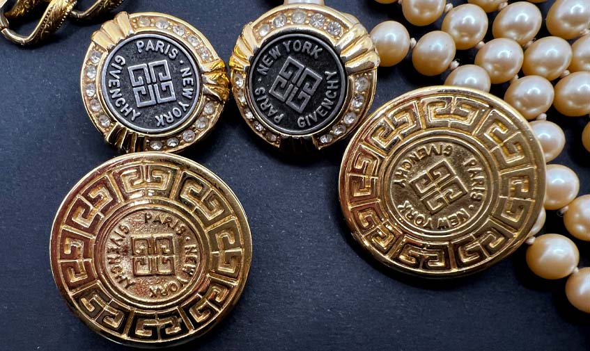 Two pairs Givenchy earrings with a pearl necklace on a black background