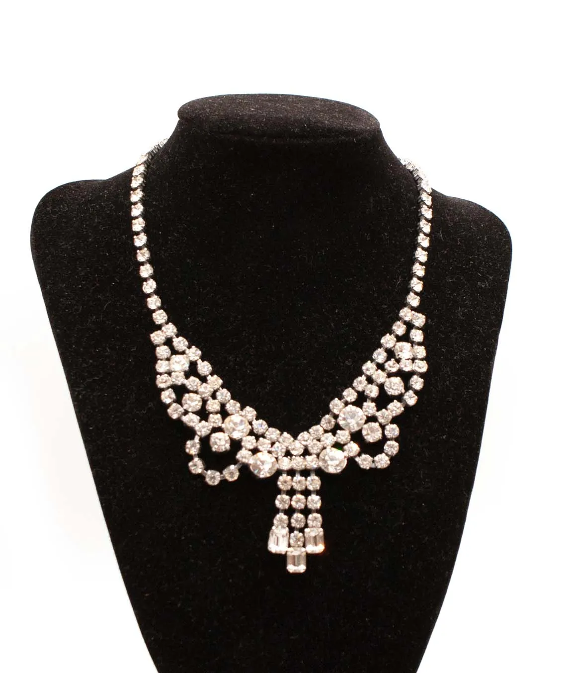Draped clear rhinestone crystal festoon necklace on silver metal on a black display