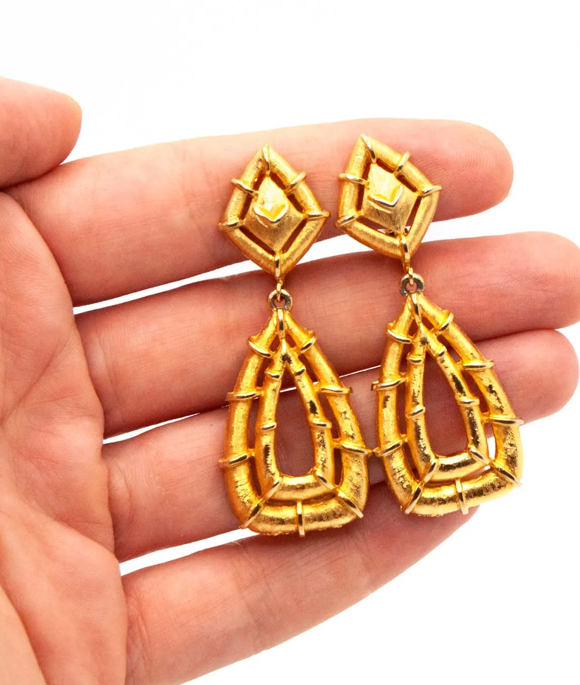 Gold bamboo clip earrings by Polcini in a hand