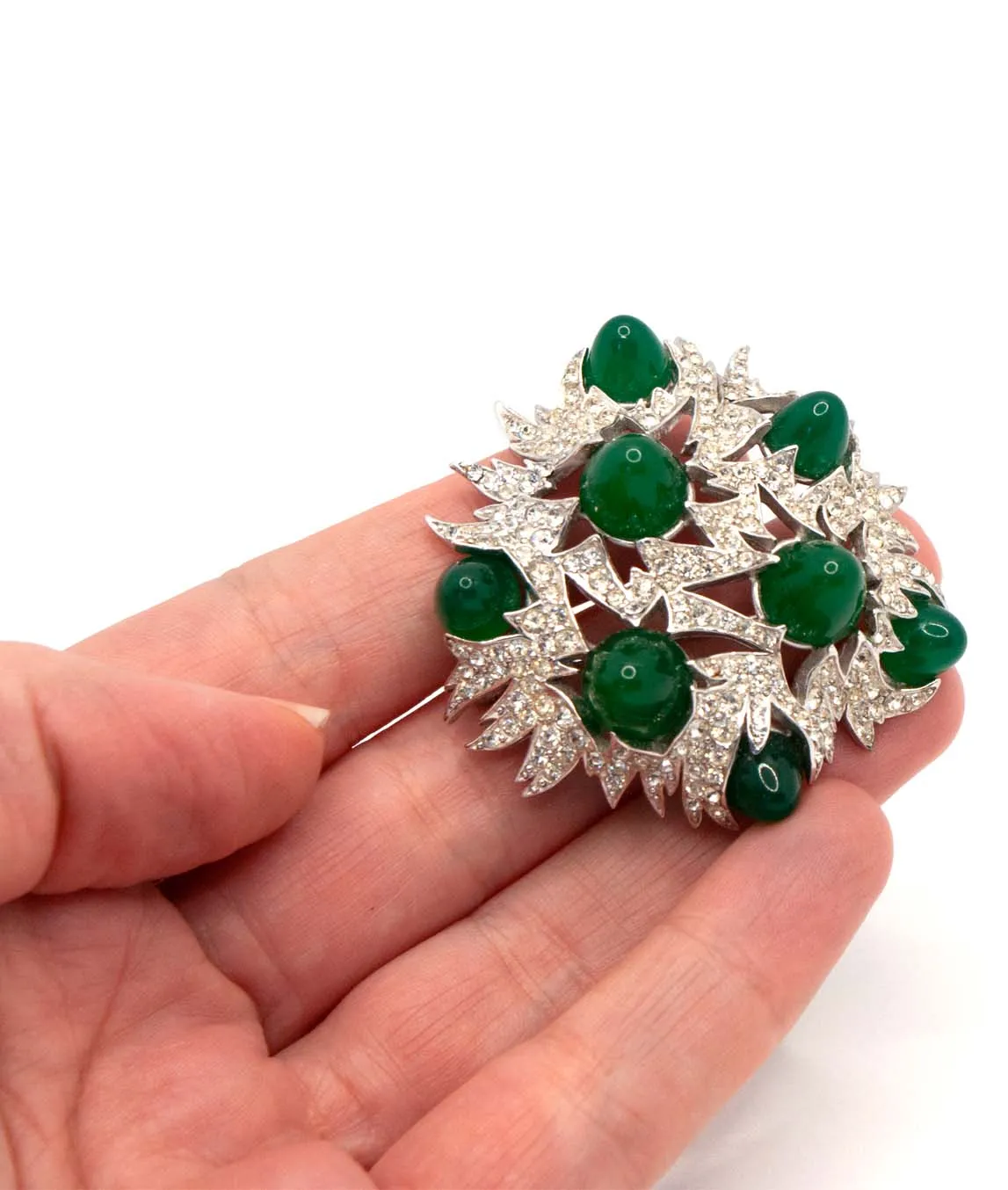 Vintage Marcel Boucher brooch with pavé crystals and green glass cabochons held in the hand