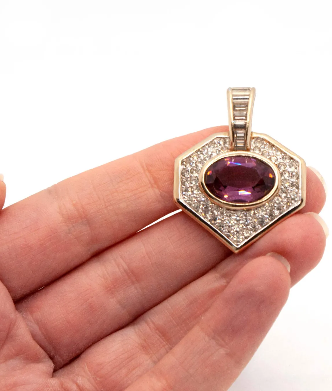 Panetta rhinestone and amethyst glass pendant set in gold plated metal held in the hand