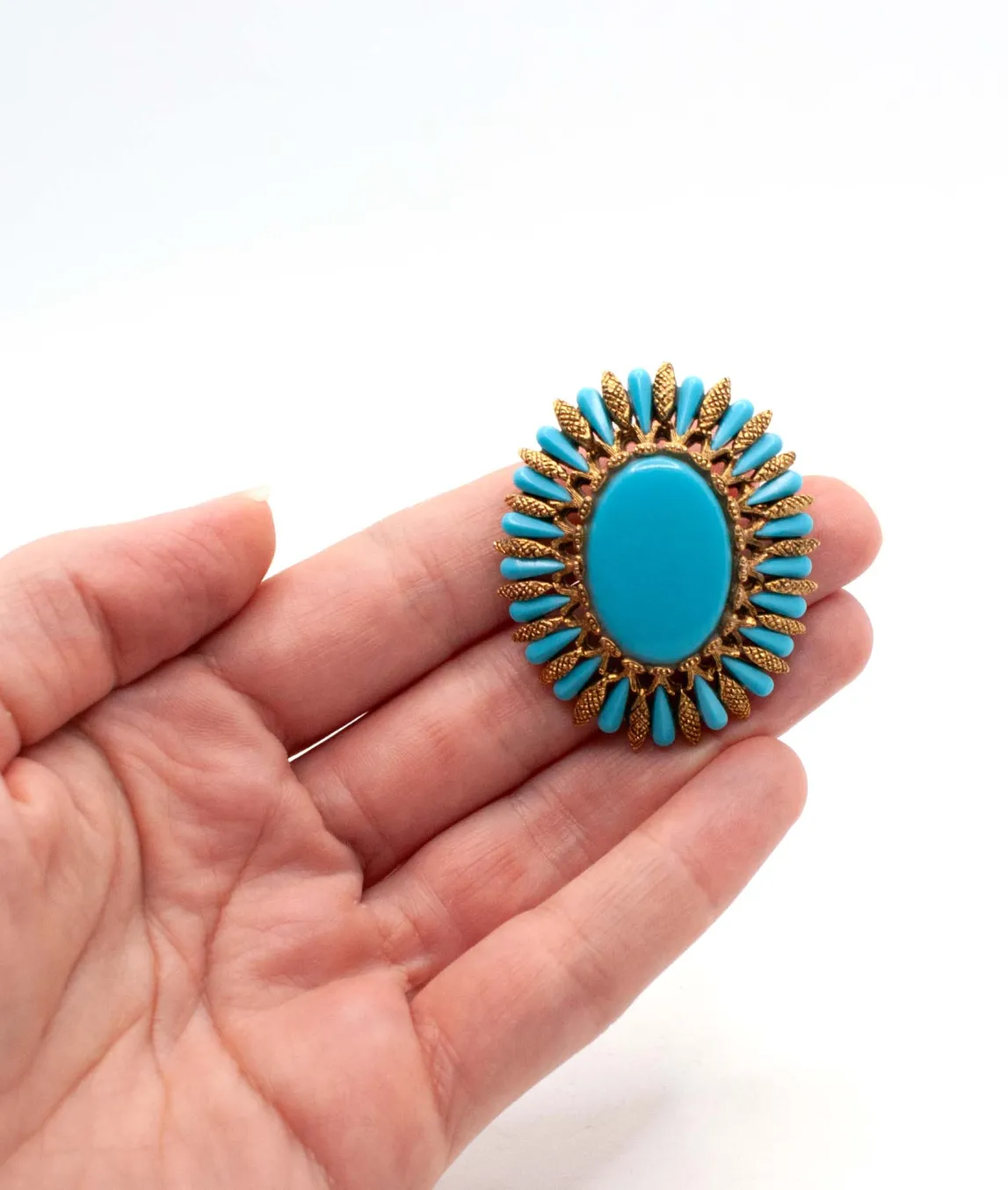 Vintage oval shaped turquoise glass brooch by HAR held in hand