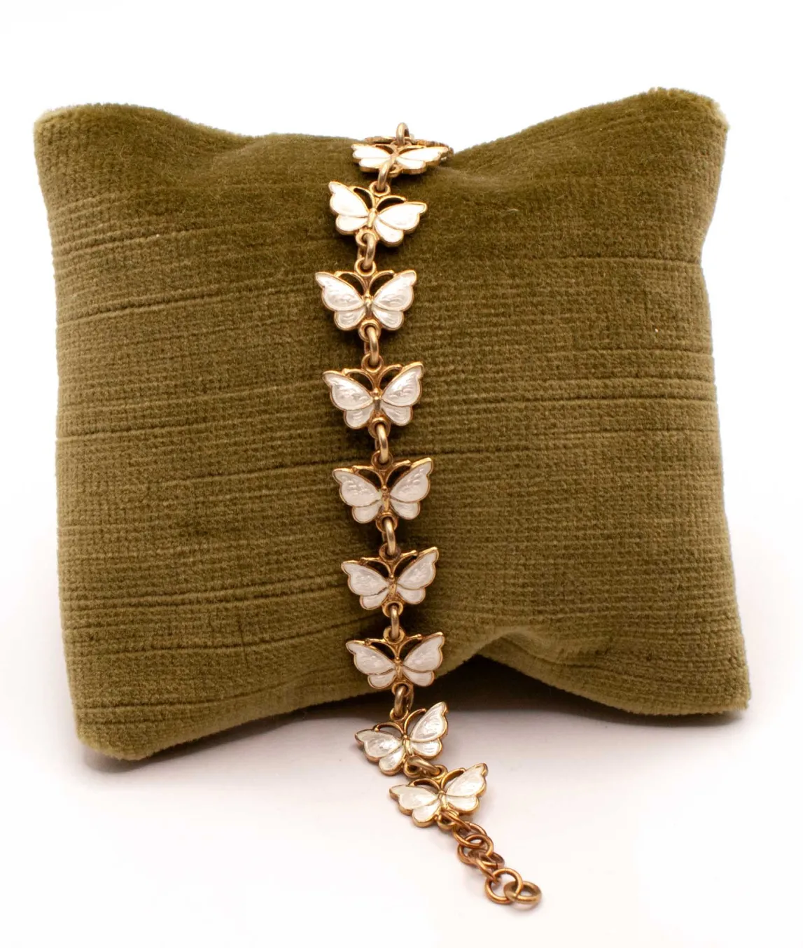 White enamel butterfly bracelet on a green pillow