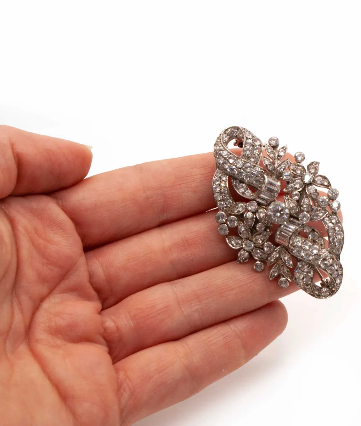 Double clip clear crystal brooch held in a hand