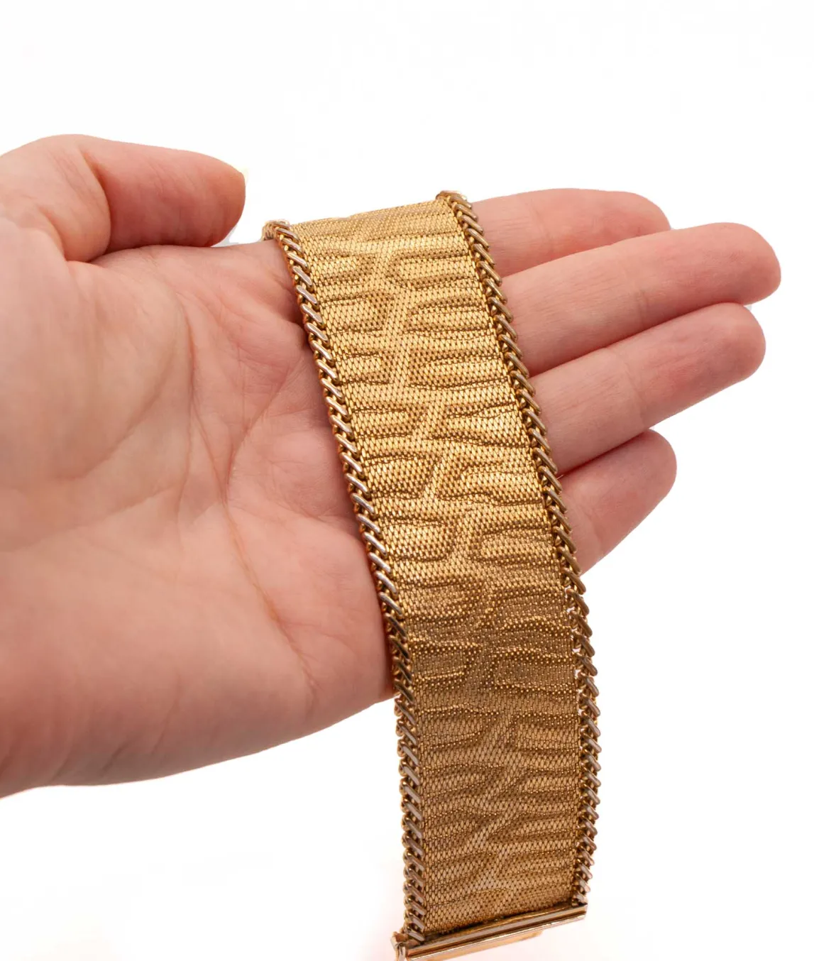 Gold tone woven bracelet featuring a leopard style print held in a hand