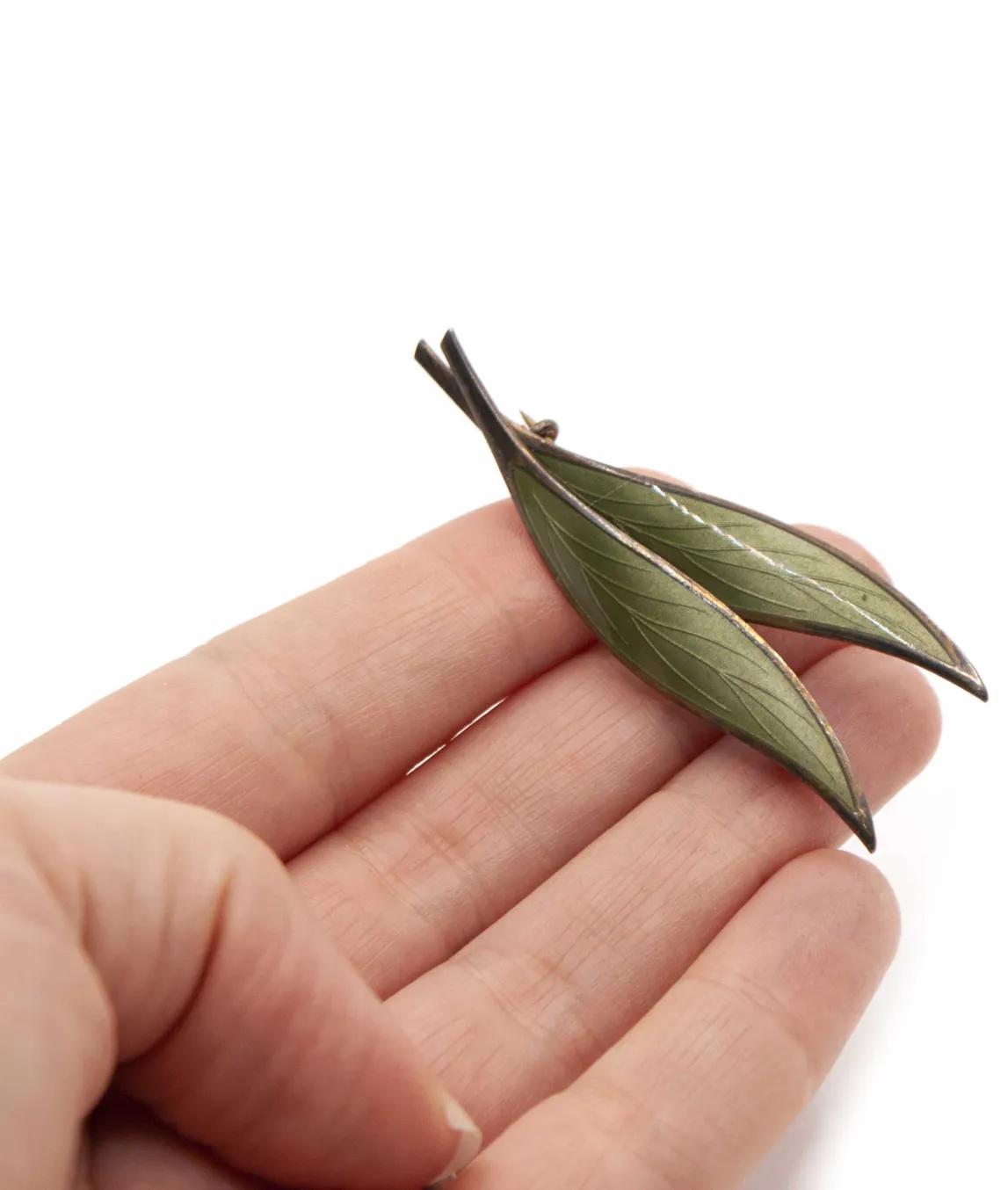 Double green enamel leaf brooch held in hand