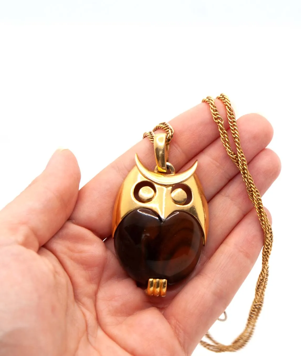 Brown and gold Trifari owl pendant held in a hand