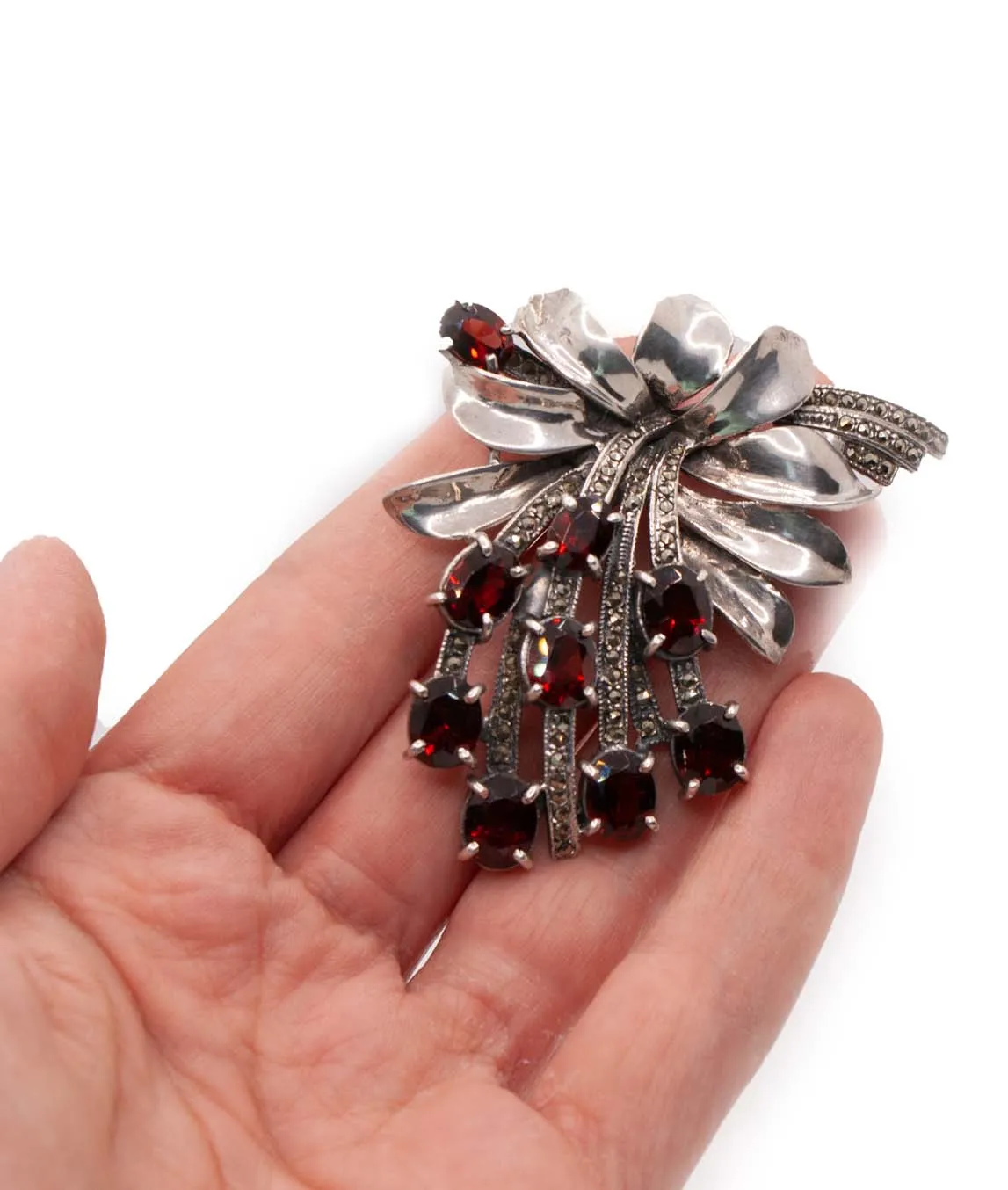 Silver and marcasite brooch with garnet red paste stones held in hand