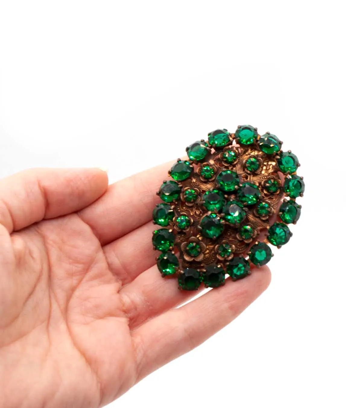 Green and copper Czech dress clip held in hand