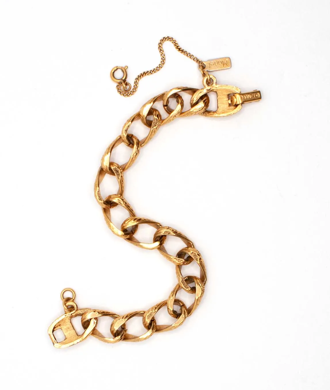 Gold tone vintage Monet charm link bracelet with safety chain shown in S shape