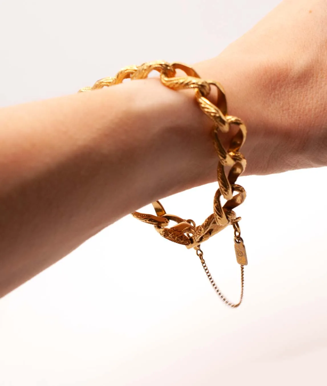 Gold coloured link bracelet with safety chain worn on wrist