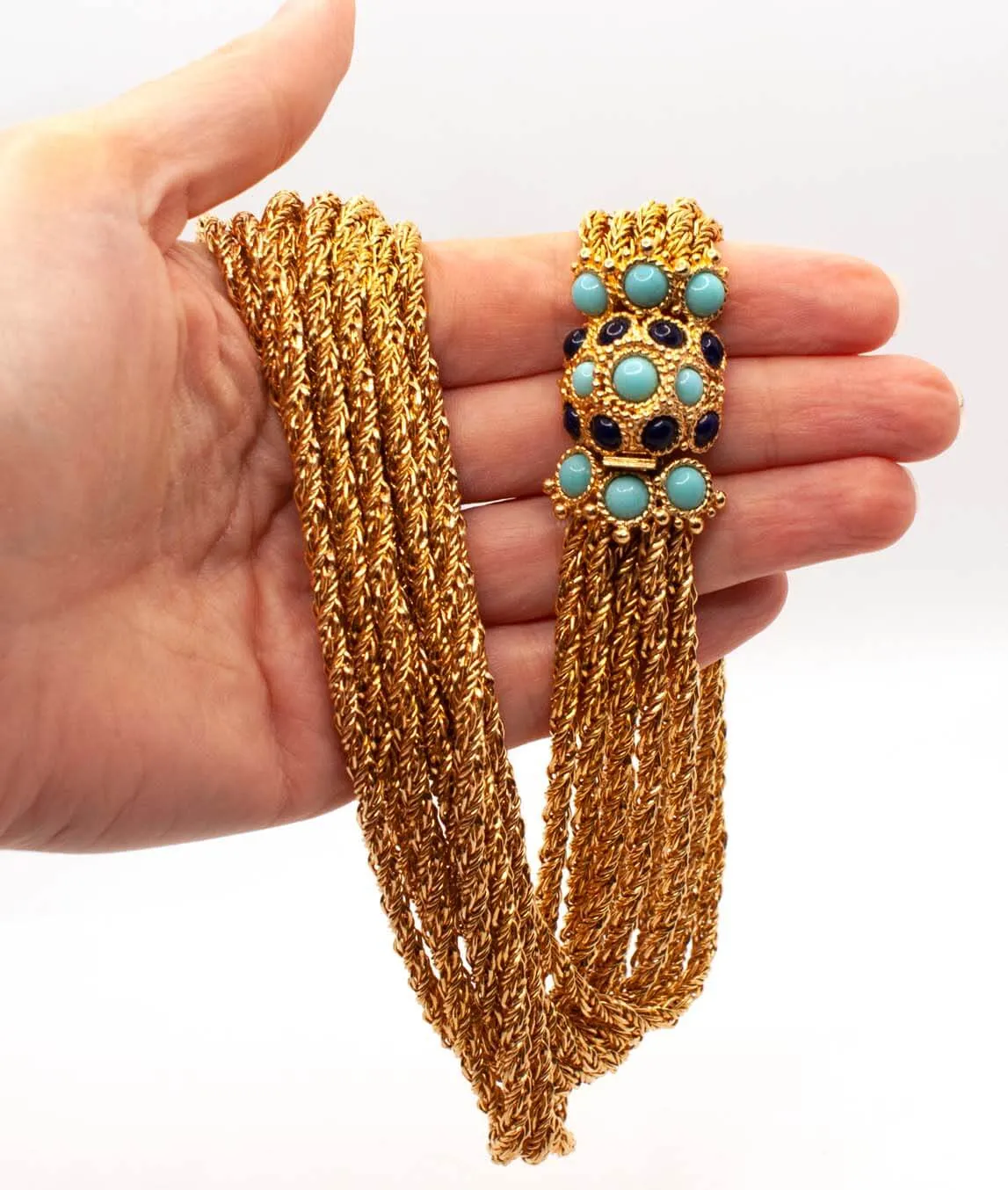 Christian Dior chain necklace with turquoise and blue glass decorative clasp held in a hand