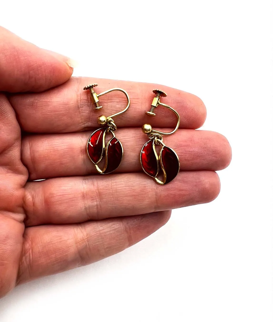 Small red enamel midcentury by David Andersen earrings held in a hand