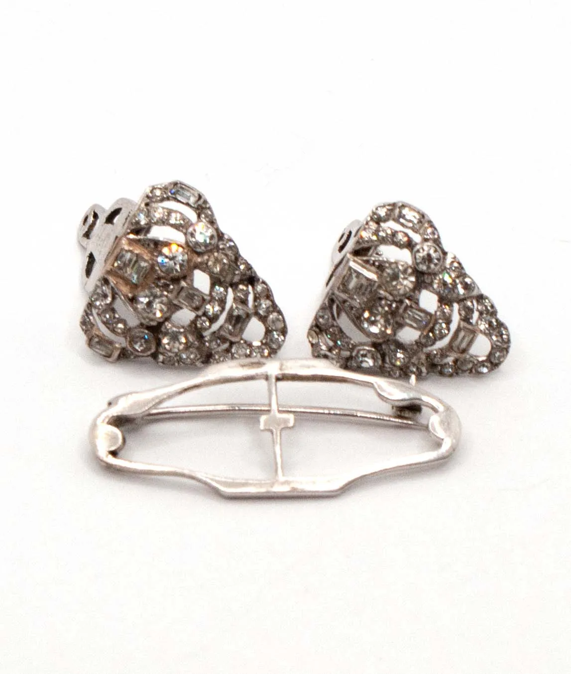 Two shield-shaped dress clips with their brooch frame - all silver with clear crystals
