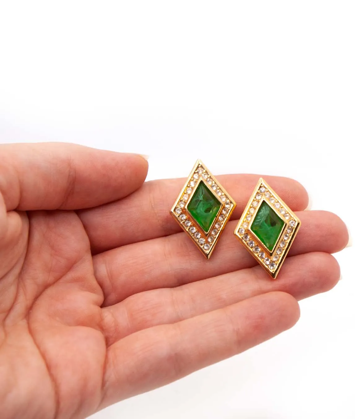 Christian Dior diamond shaped clip earrings with flawed emerald art glass and rhinestones held in hand