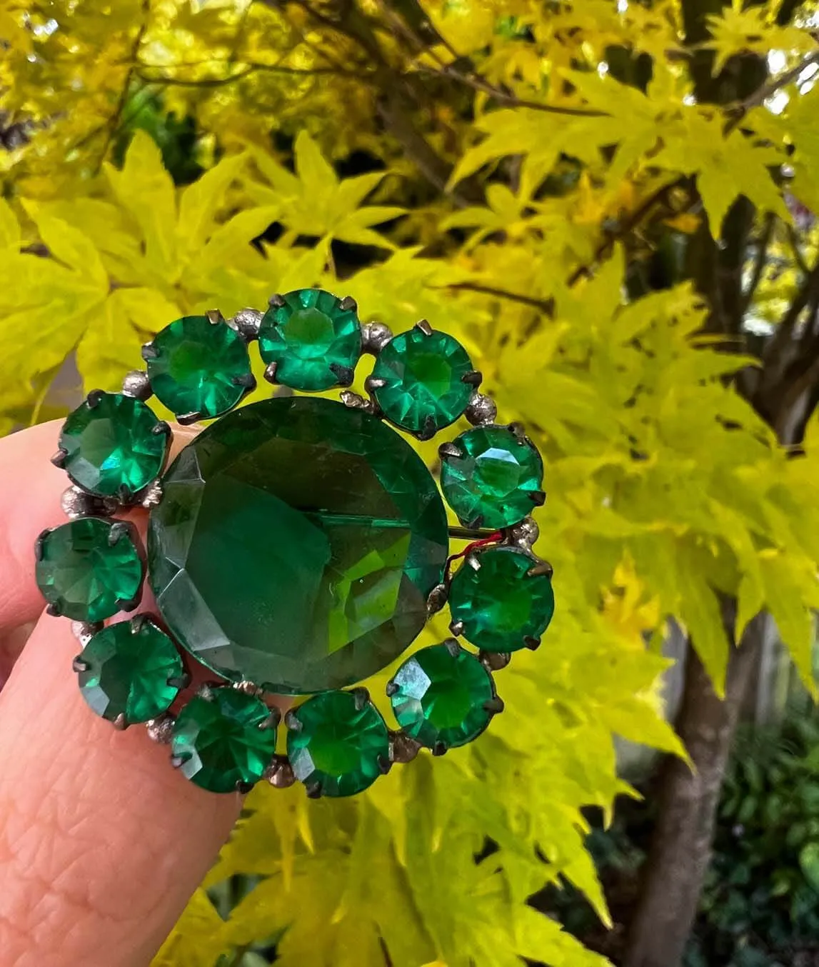 Green glass midcentury brooch on yellow background