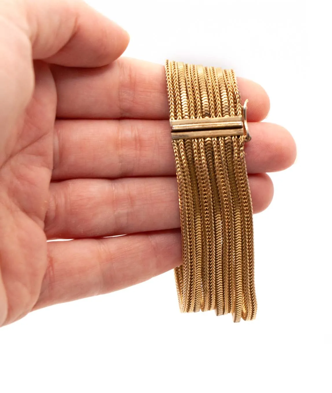 Grosse multi-chain woven gold plated bracelet held in hand