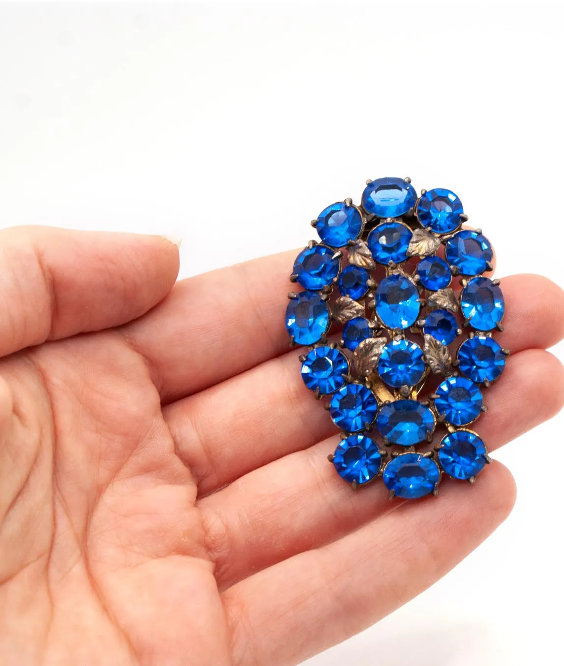 Large blue crystal dress clip held in a hand