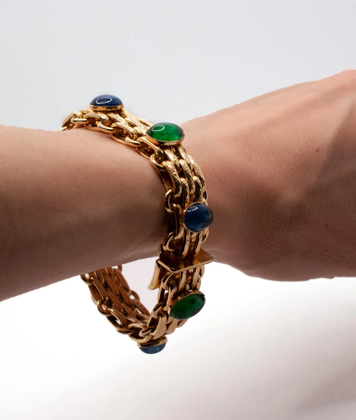 Large gold-plated link Christian Dior bracelet decorated with green and blue on a wrist