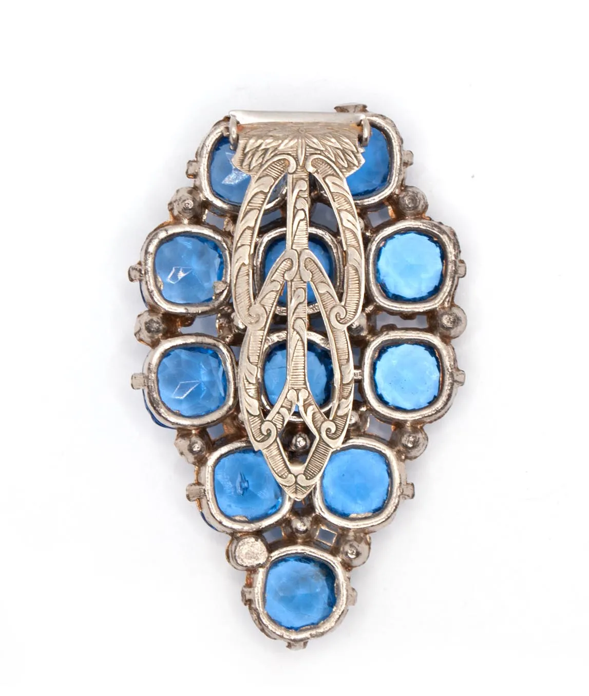 Back of a vintage dress clip with an engraved clip and open back settings for light blue gems