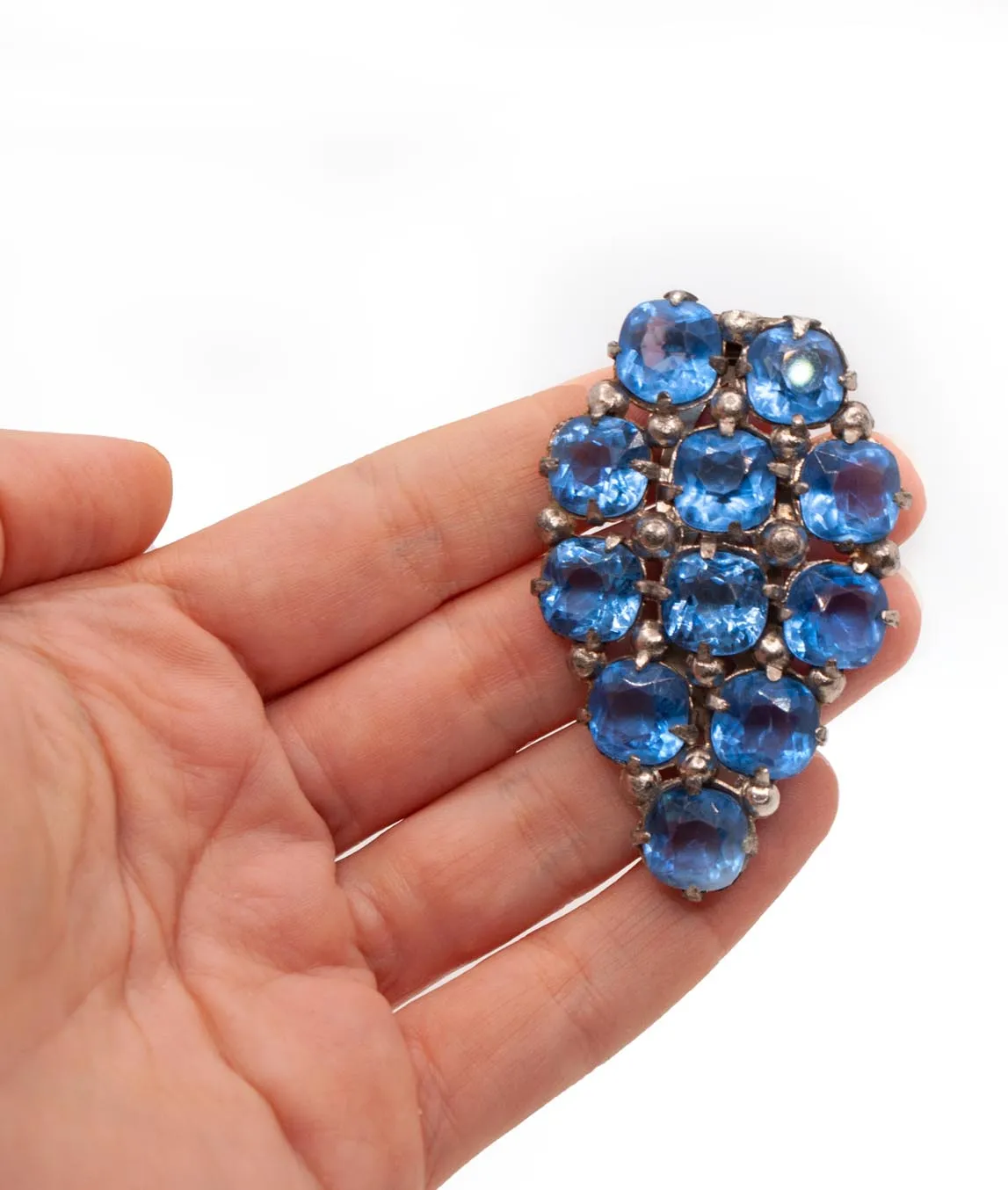 Blue glass dress clip held in a hand