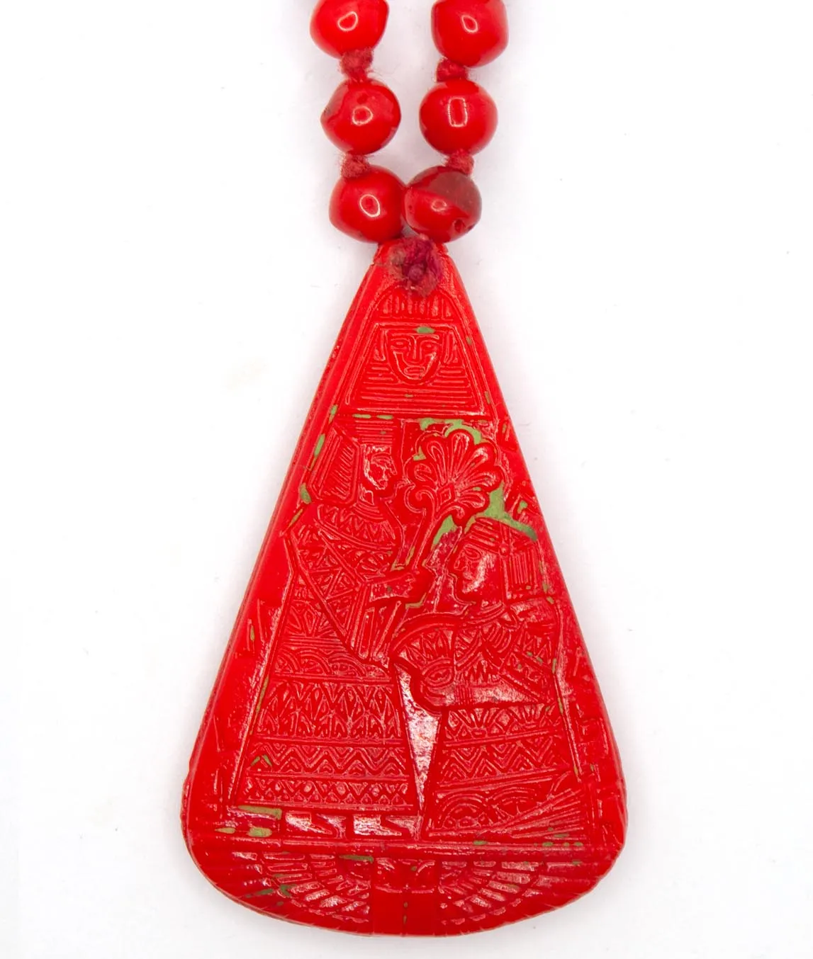 Close up of large red pendant in pear-shape with remnants of green paint on Neiger brothers necklace
