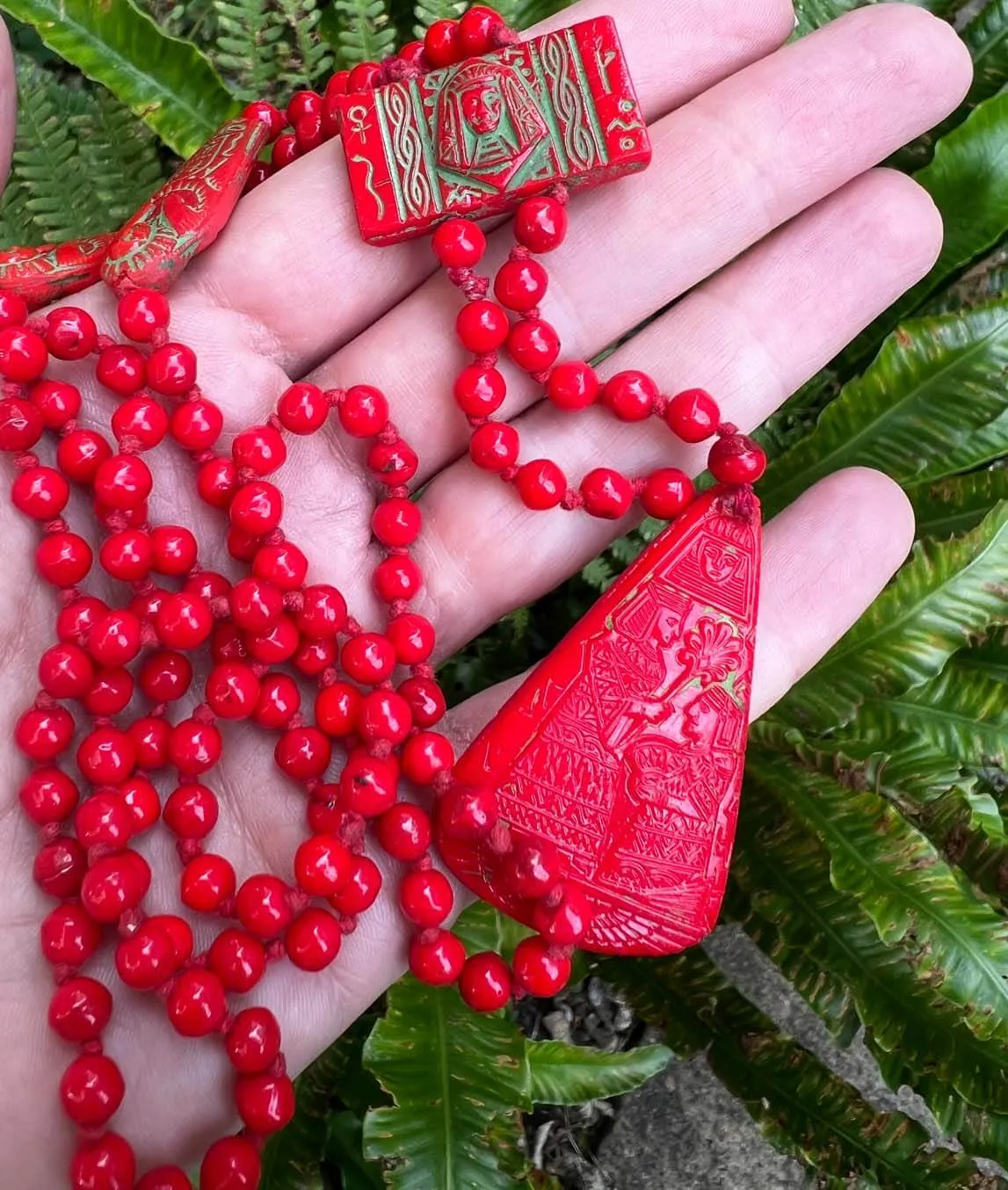 Neiger Brothers red bead Egyptian Revival necklace with pendant on leafy background