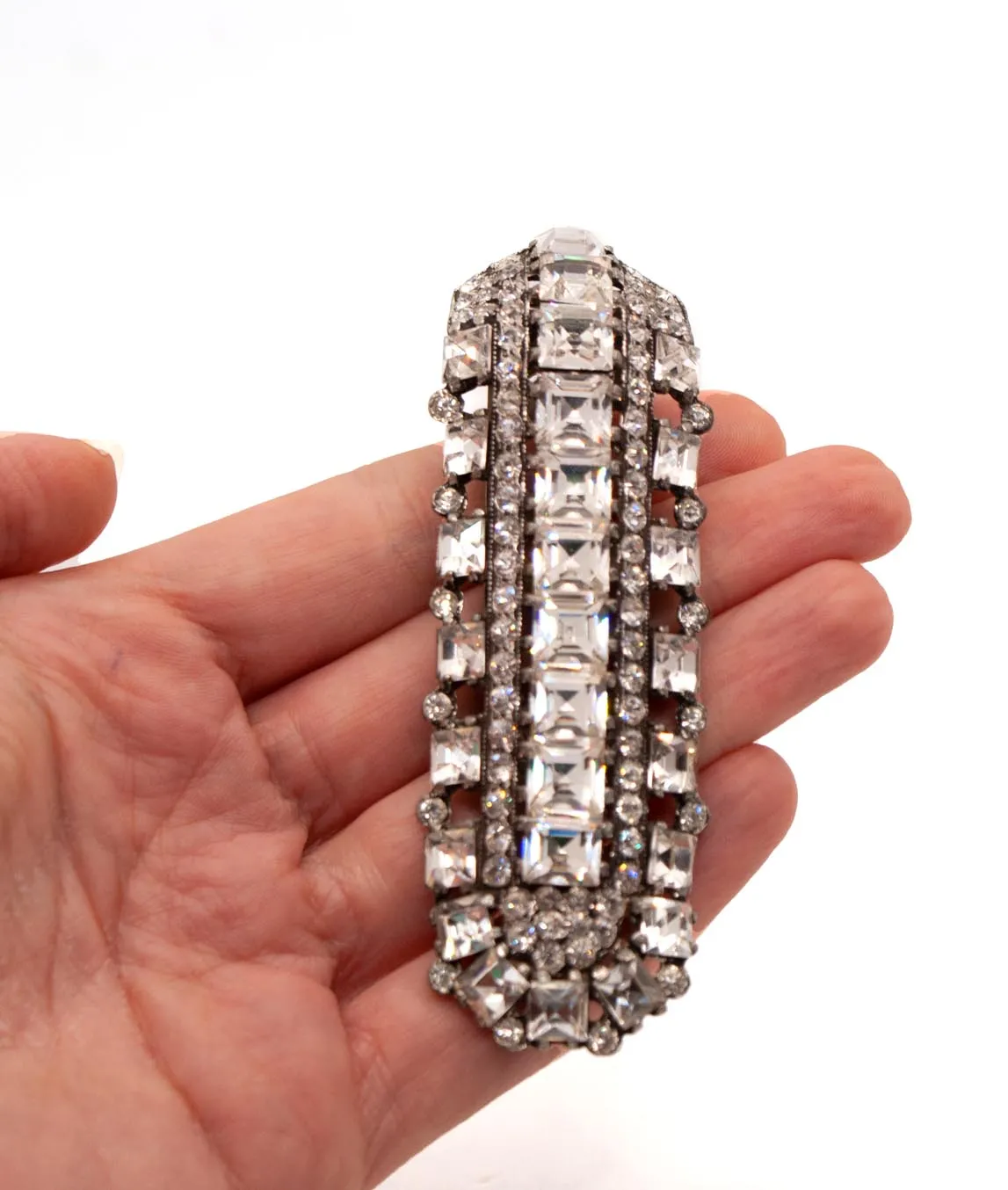 Long crystal dress clip with square and round pastes held in a hand