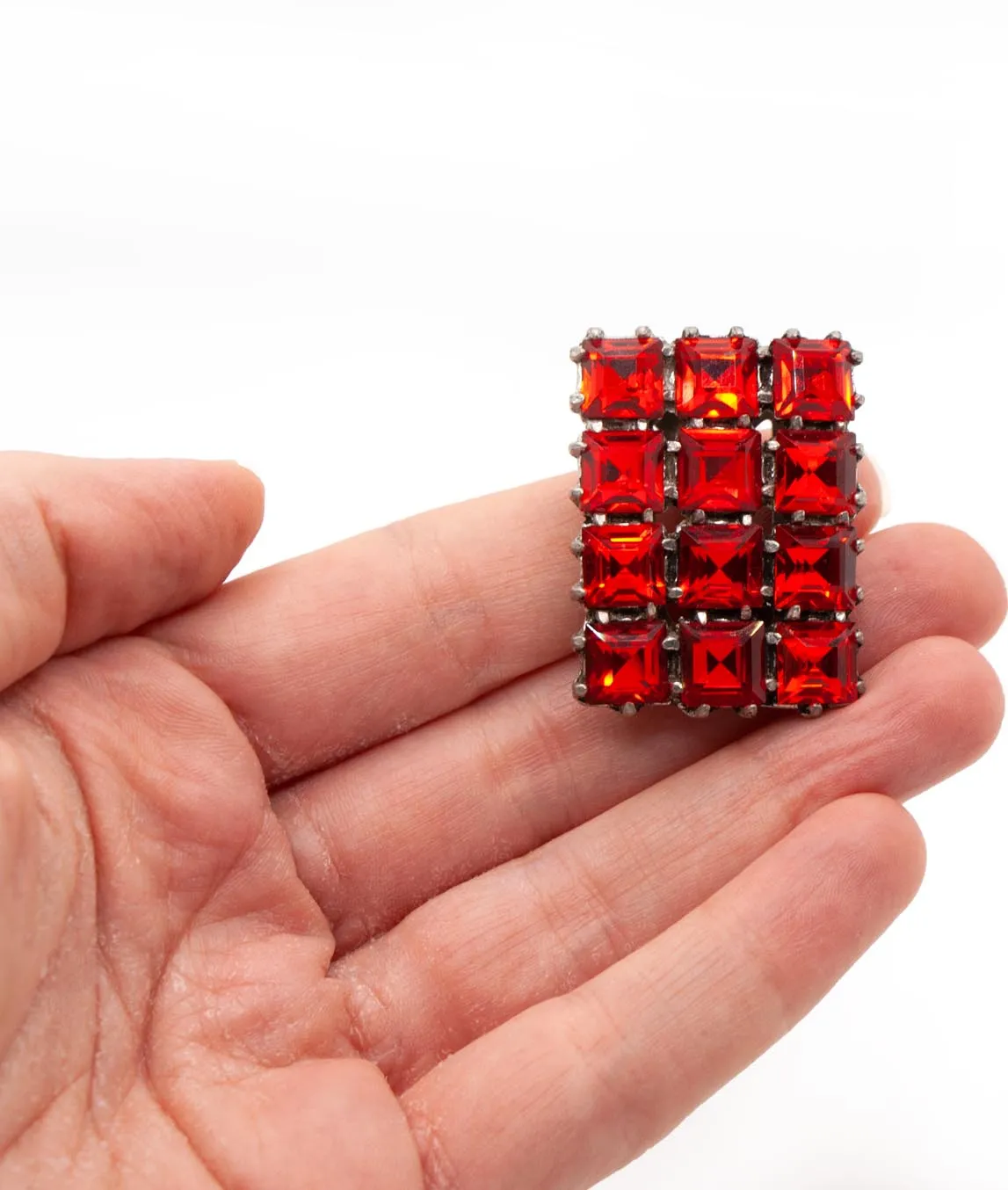 Red rectangular dress clip with square pastes held in a hand