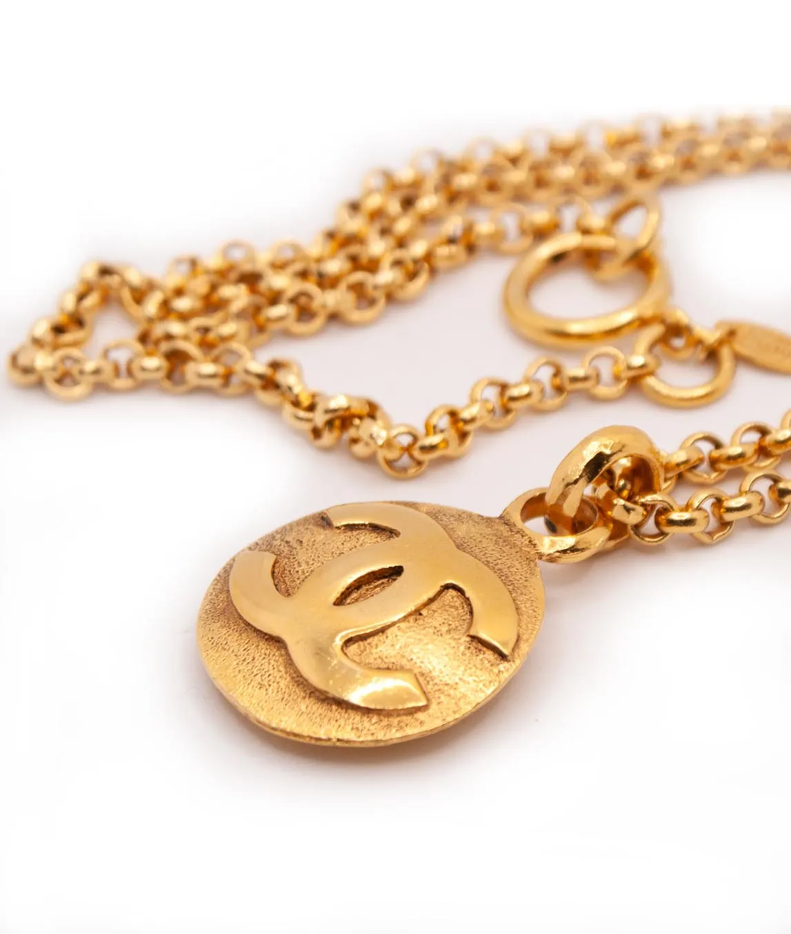 Profile view of round CC Chanel logo pendant on gold-plated chain from 1990 with oversized clasp