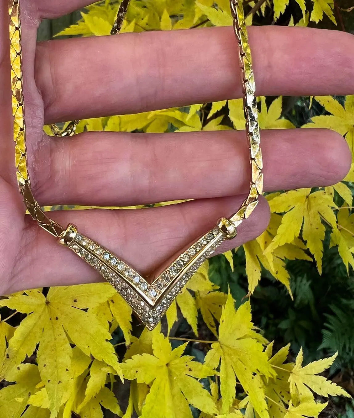 Vintage 1980s Christian Dior gold-tone chain with rhinestone v decoration with yellow leaf background