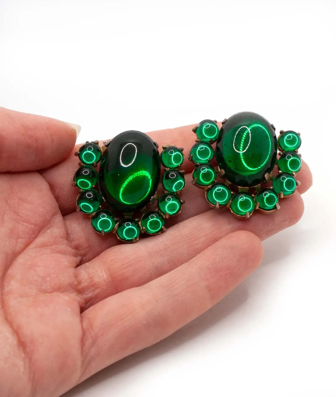 Pair of green glass cabochons dress clips held in a hand