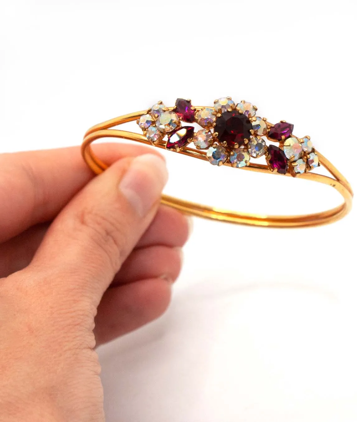 Red and AB rhinestone gold tone vintage Austrian bangle bracelet held in a hand