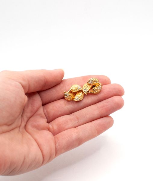 Small gold coloured Christian Dior earrings in a hand