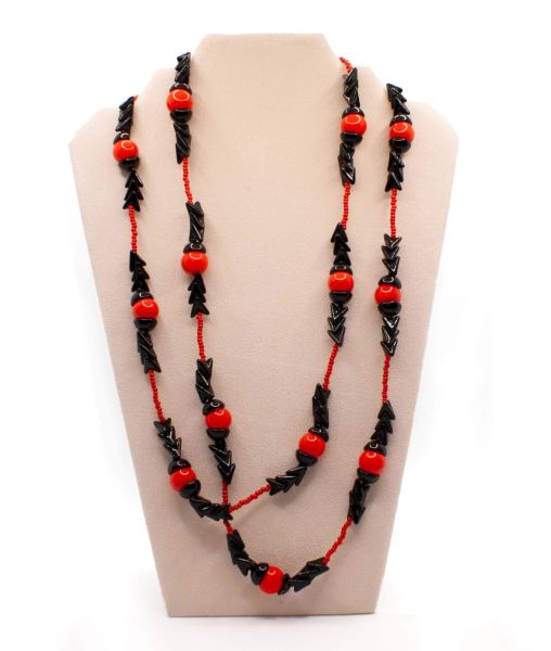 Long beaded necklace by Miriam Haskell with red and black arrow beads on a display