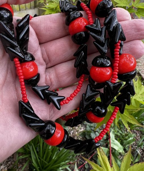 Long beaded necklace by Miriam Haskell with red and black arrow beads in natural light
