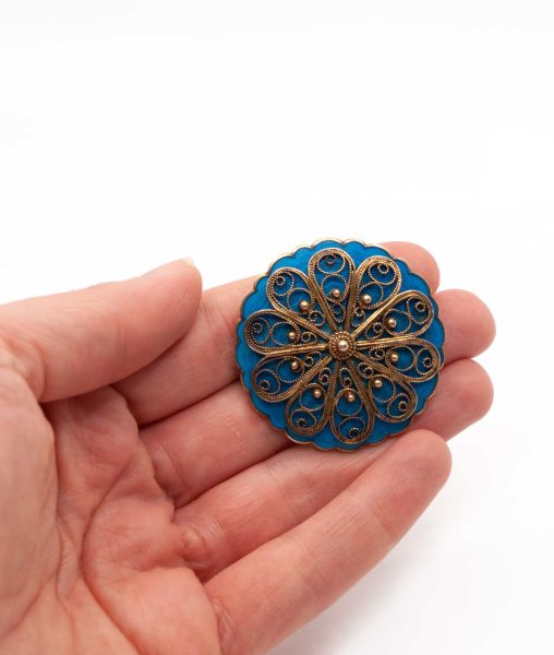 Round blue enamel vintage brooch held in hand